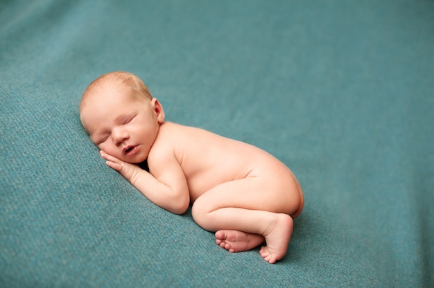 Neonato che dorme in un servizio fotografico neonato con le mani sotto le guance.