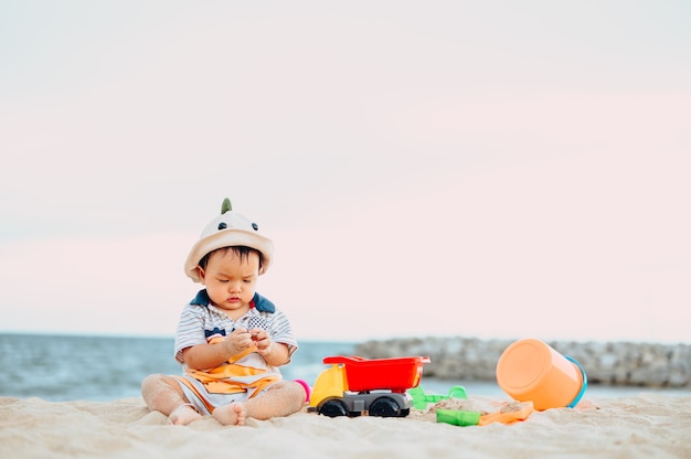 Neonato che gioca con i giocattoli da spiaggia con sua madre sulla spiaggia tropicale.