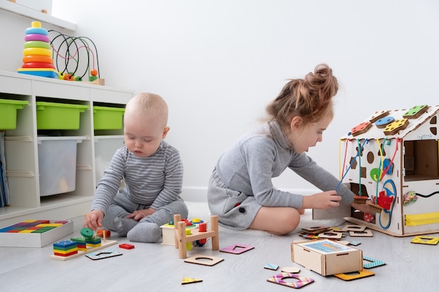 Neonato che gioca con la sorella maggiore con i giocattoli di legno. sviluppo precoce dei bambini.