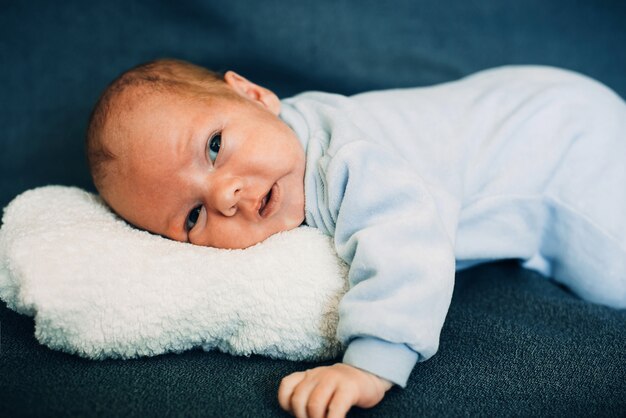 Neonato che si trova sul cuscino bianco della peluche