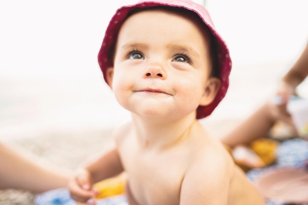 Neonato con cappello seduto su una spiaggia