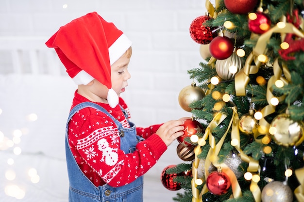 Neonato divertente felice con i regali per natale su fondo del concetto dell'albero di natale delle feste