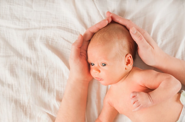 Neonato e mani sul primo piano letto. Il concetto di relazione tra figli e genitori dalla nascita.