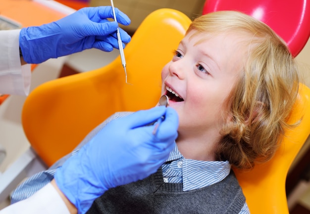 Neonato sorridente con capelli ricci biondi in poltrona.