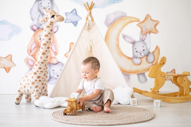 Neonato sveglio che gioca con i giocattoli naturali di legno nella stanza dei bambini a casa giocattoli educativi per bambini