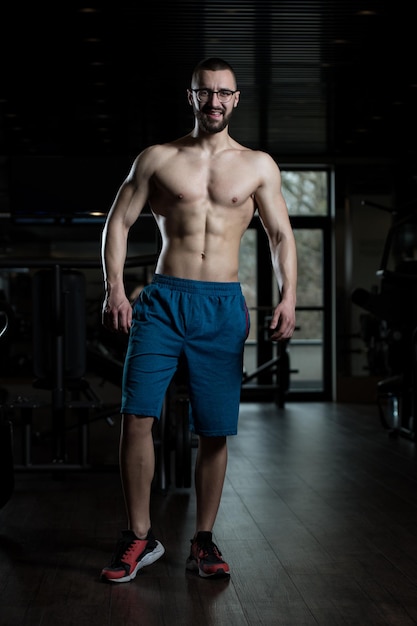 Nerd uomo in piedi forte in palestra