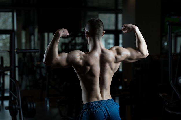 Nerd uomo in piedi forte in palestra