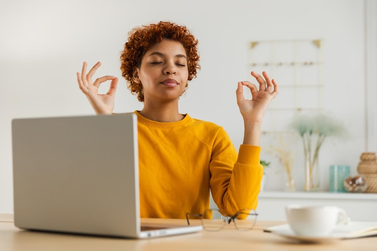 Foto nessun stress, mantenete la calma. una donna d'affari africana pratica esercizi di respirazione in ufficio a casa.