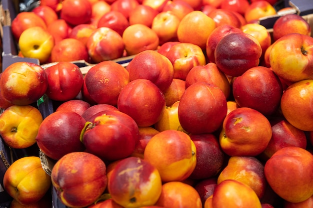 Nettarina appena raccolta deliziosa variopinta in scatole di carta al mercato dell'agricoltore della drogheria. Per l'agricoltura, sfondo illustrazione cibo