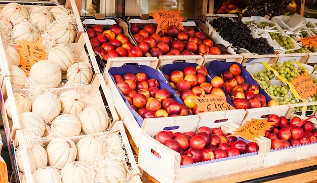 Nettarine di frutta fresca, uva bianca e nera, meloni bianchi in un mercato