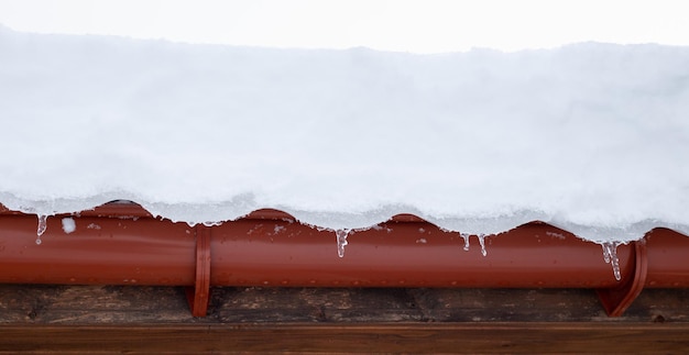 Neve che cade dal tetto della casa Clima invernale con forti nevicate