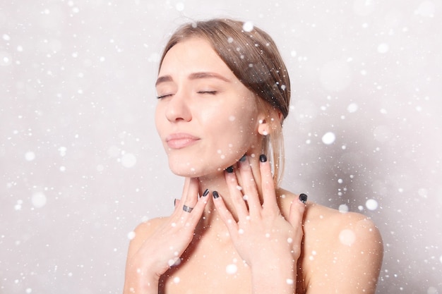 Neve, inverno, natale, malattia, assistenza sanitaria, persone, concetto di medicina - dolore alla gola. Primo piano di donna malata con mal di gola che si sente male. Bella ragazza che tocca il collo con la mano sullo sfondo della neve