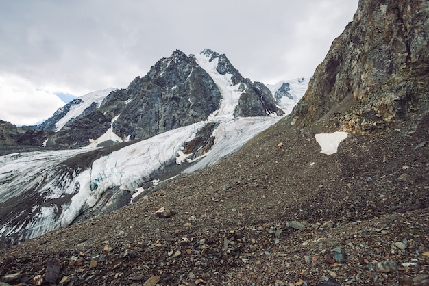 Neve sulla catena montuosa. Atmosferica cresta nevosa sotto il cielo nuvoloso. Rocce giganti insolite in tempo nuvoloso. Salire in alta montagna. Incredibile paesaggio minimalista della maestosa natura degli altopiani.