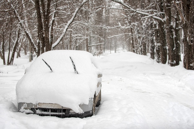 Neve sulle auto nel parco dopo la nevicata. Scena urbana invernale