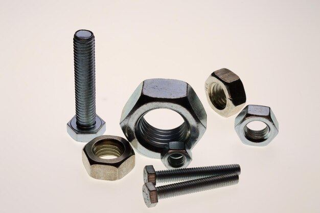 new chromeplated bolts and nuts of different sizes lie on a white background closeup