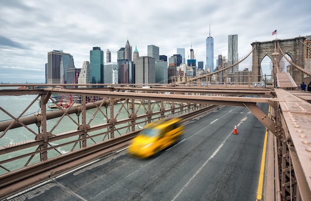 New York, Usa - 29 aprile 2016: Auto che attraversano il ponte di Brooklyn a New York in una giornata nuvolosa. Sullo sfondo lo skyline di Manhattan