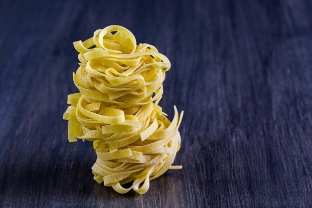 Nidi di fettuccine biologiche su tavola di legno.