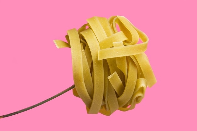 Nido di pasta secca su uno sfondo rosa in una vista ravvicinata