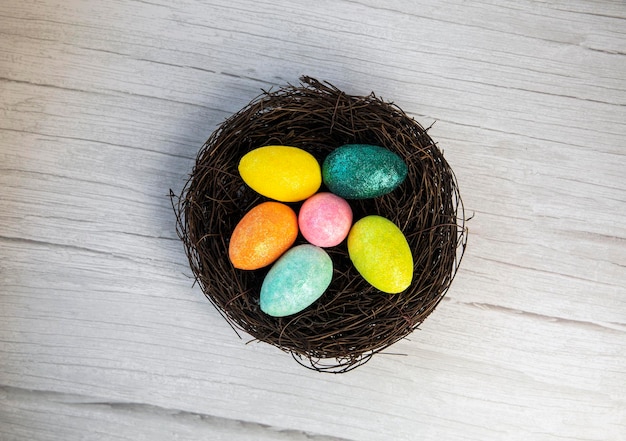 Nido di uova di Pasqua colorato con sfondo di legno extra bianco o grigio per stanza o spazio per la copia...