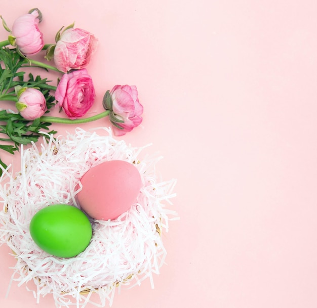 Nido di uova di Pasqua e bouquet di fiori di Buttercups su sfondo rosa pastello spazio copia