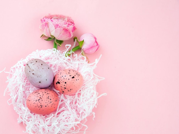Nido di uova di Pasqua e bouquet di fiori di Buttercups su sfondo rosa pastello spazio copia