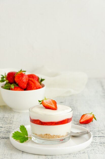 Niente cheesecake alla fragola al forno in un bicchiere. Dessert freddo estivo.