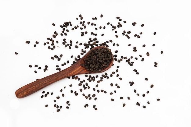 Nigella o cumino nero con un tulsi medicinale Seeds WhiteBackground Brown Spoon