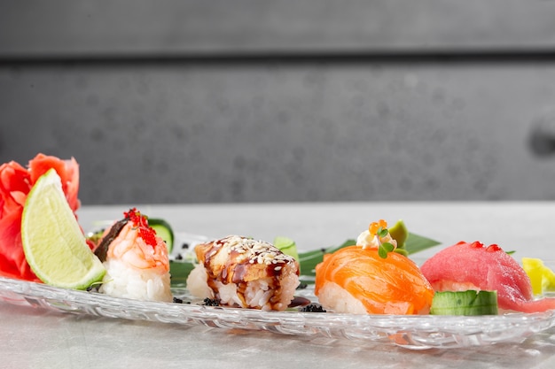 Nigiri sushi con salmone, anguilla, tonno e gamberi, servito su un piatto trasparente.