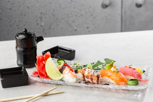 Nigiri sushi con salmone, anguilla, tonno e gamberi, servito su un piatto trasparente.