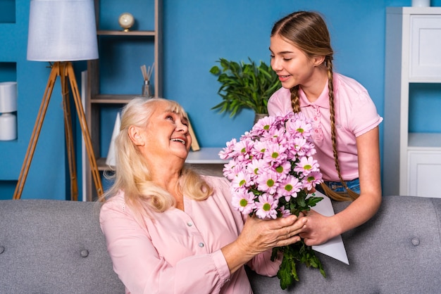 Nipote che presenta fiori alla nonna a casa, momenti felici della vita domestica