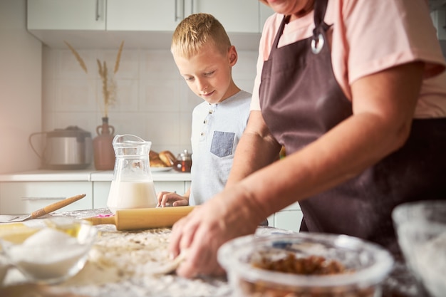 Nipote desideroso che guarda sua nonna impastare la pasta per i biscotti