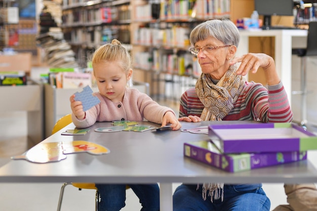 Nipote e nonna mettono insieme un puzzle nella biblioteca della città