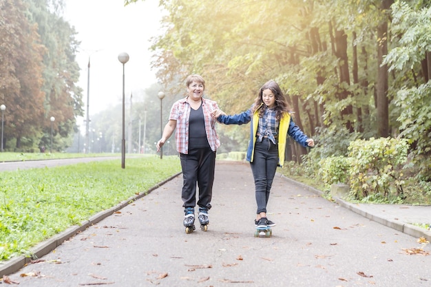 Nipote e nonna sui rollerblade e sullo skateboard nel parco