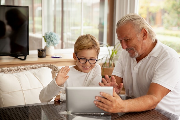 Nipote e nonno che parlano tramite l'app di chat video utilizzando il tablet