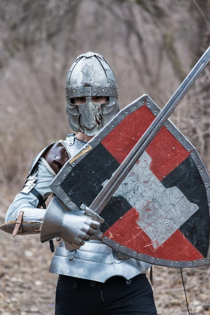 Nobile guerriero Ritratto di un guerriero medievale o cavaliere in armatura e casco con scudo e spada in posa