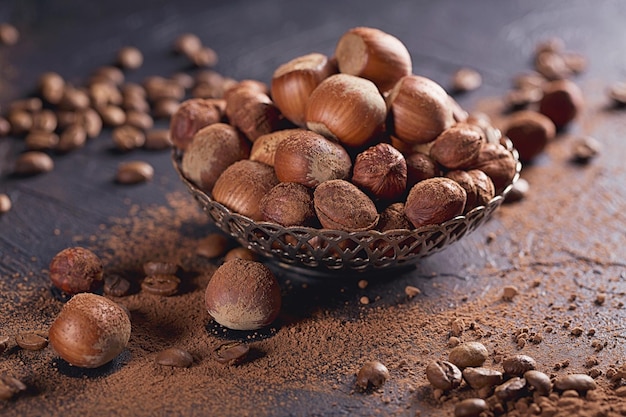 Nocciola, chicchi di caffè e cacao in polvere su sfondo scuro. Ingredienti per cucinare dolci al cioccolato fatti in casa. Concetto di dolci e dolci