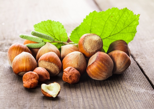 Nocciole con guscio e foglia verde sul tavolo di legno