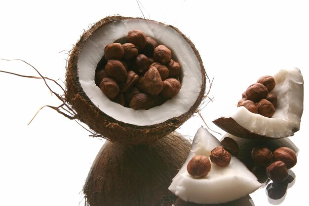 Nocciole in una noce di cocco divisa su sfondo bianco