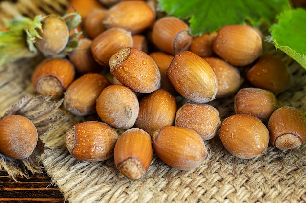 Nocciole su un fondo di legno con foglie verdi. Contiene vitamine e minerali benefici.