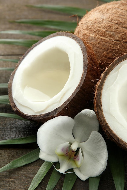 Noce di cocco con foglie e fiori su fondo di legno grigio