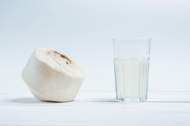 Noce di cocco con un bicchiere di acqua di cocco fresca