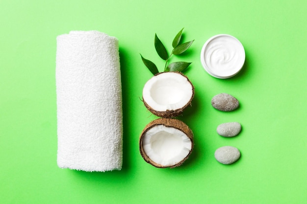 Noce di cocco con vasetti di olio di cocco e crema cosmetica su sfondo colorato Vista dall'alto Spazio libero per il testo Cosmetici spa naturali al cocco e concetto di trattamento biologico Composizione Spa al cocco