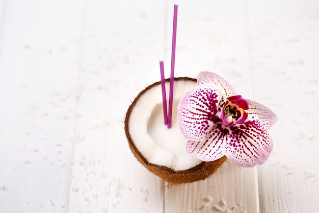 Noce di cocco decorata con l'orchidea sulla tavola di legno