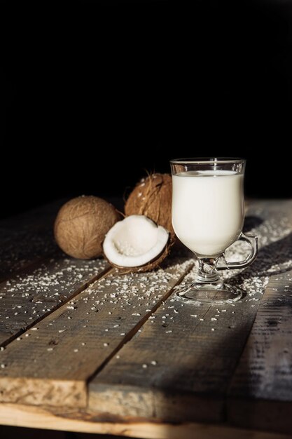 Noce di cocco e latte di cocco rotto noce di cocco su tavole di legno sullo sfondo