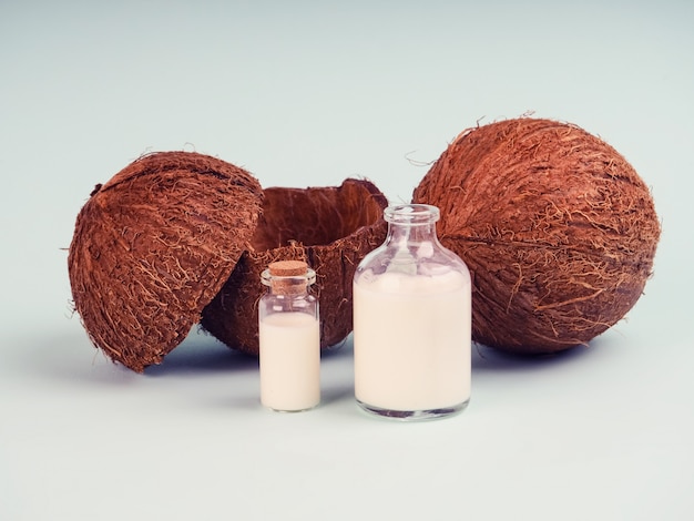 Noce di cocco e latte di cocco sulla tavola blu. Olio di cocco con noci fresche. latte di cocco, olio di truciolo in provetta per ricerca, superfood, olio naturale, cosmetici