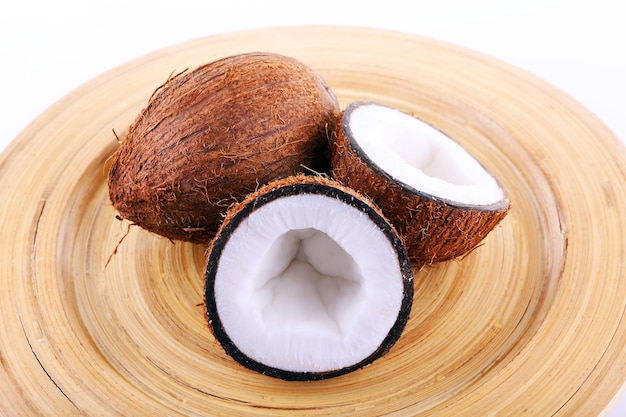 Noce di cocco tagliata a metà su tagliere di legno e sfondo bianco
