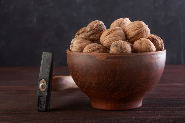 Noce in ceramica e martello su un tavolo di legno