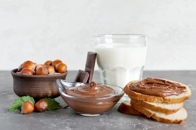 Noci di cioccolato da spalmare con latte e toast croccanti per colazione Composizione sul primo piano del tavolo