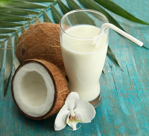 Noci di cocco con bicchiere di latte su fondo di legno blu