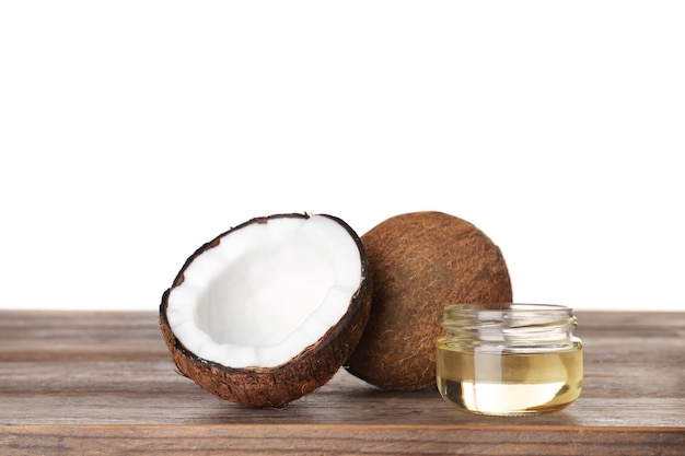 Noci di cocco e barattolo di olio biologico naturale su tavola di legno su sfondo bianco